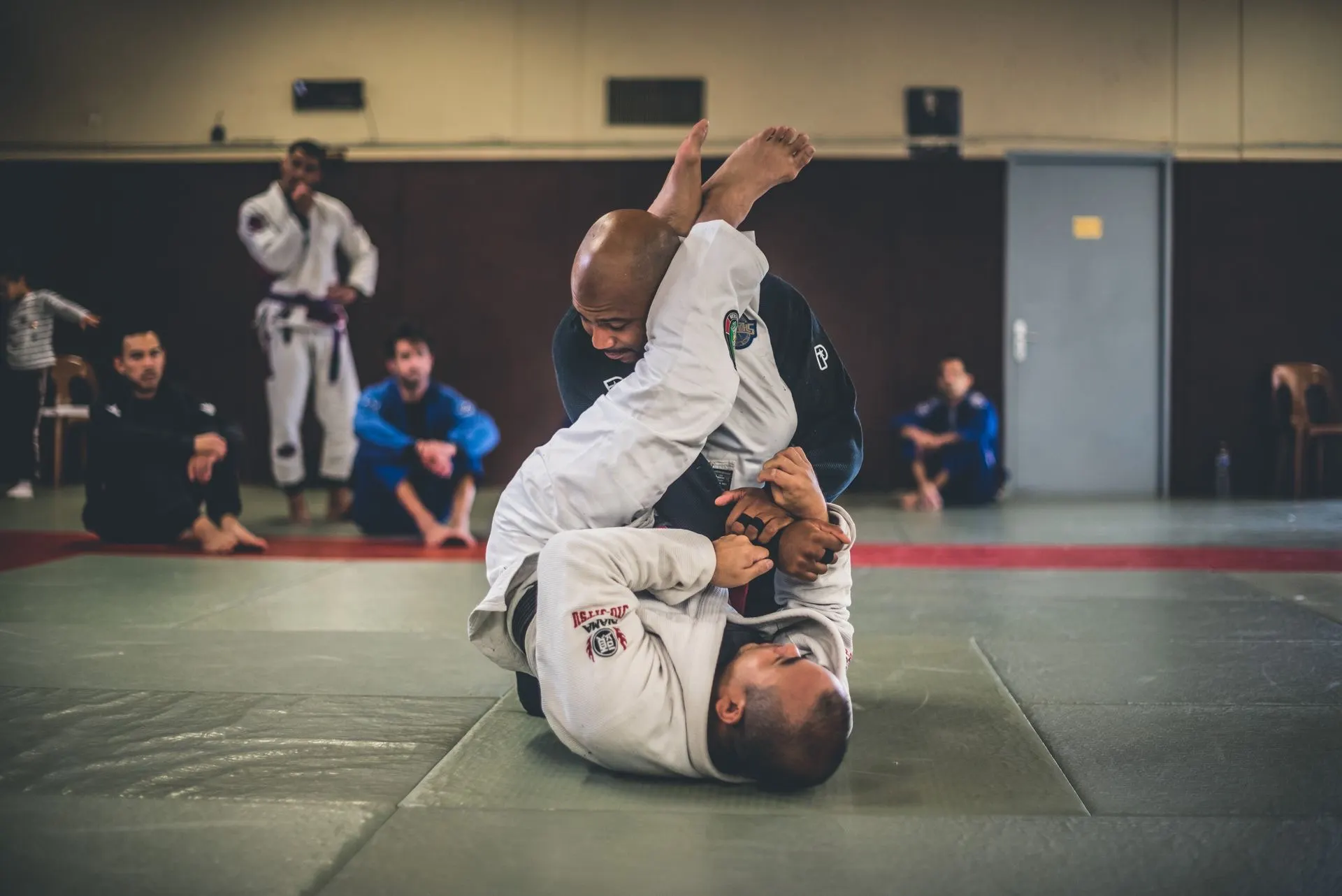 Combat en kimono devant les autres pratiquants assis au bord du tapis
