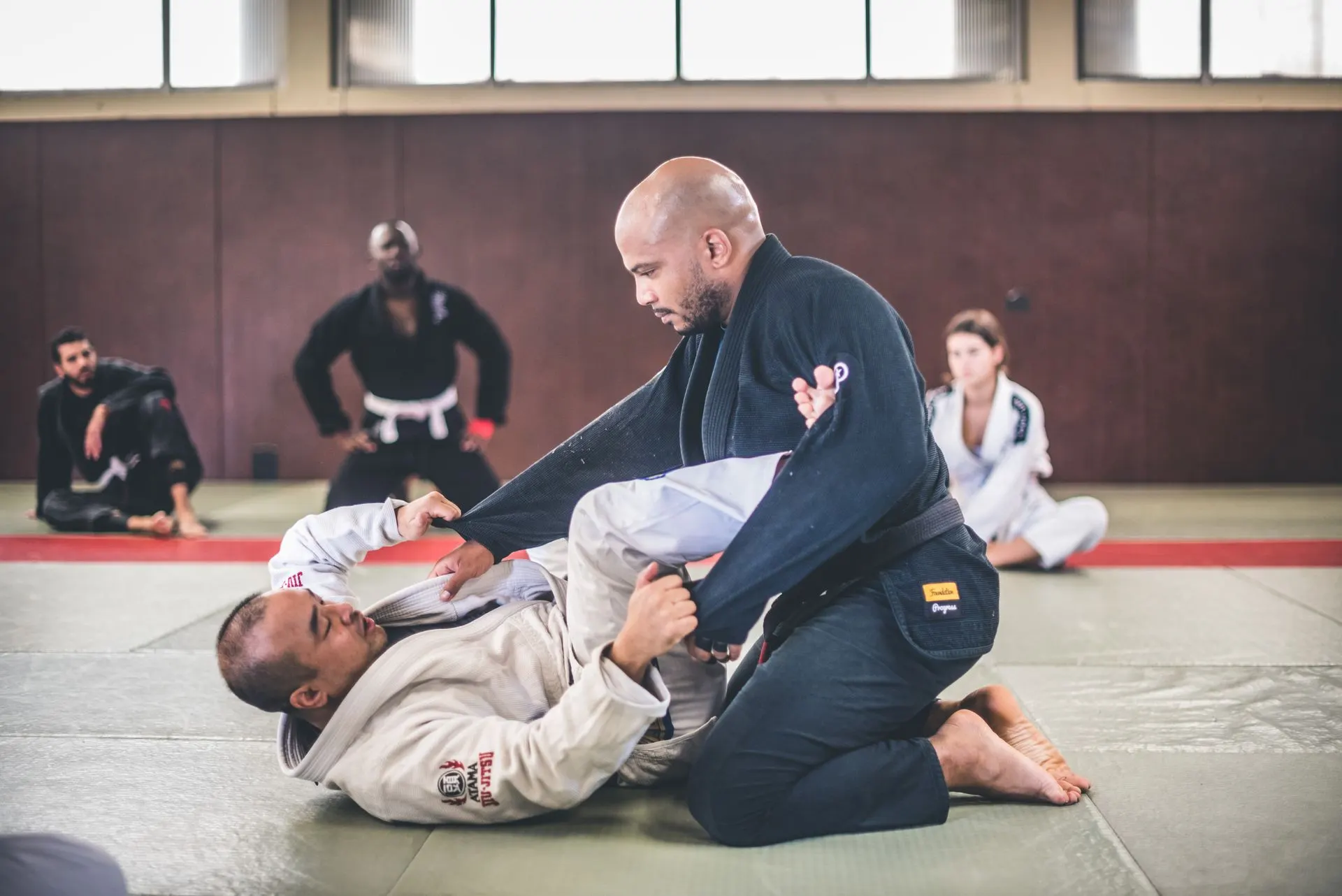 Un coach en kimono bleu contrôle un partenaire au sol