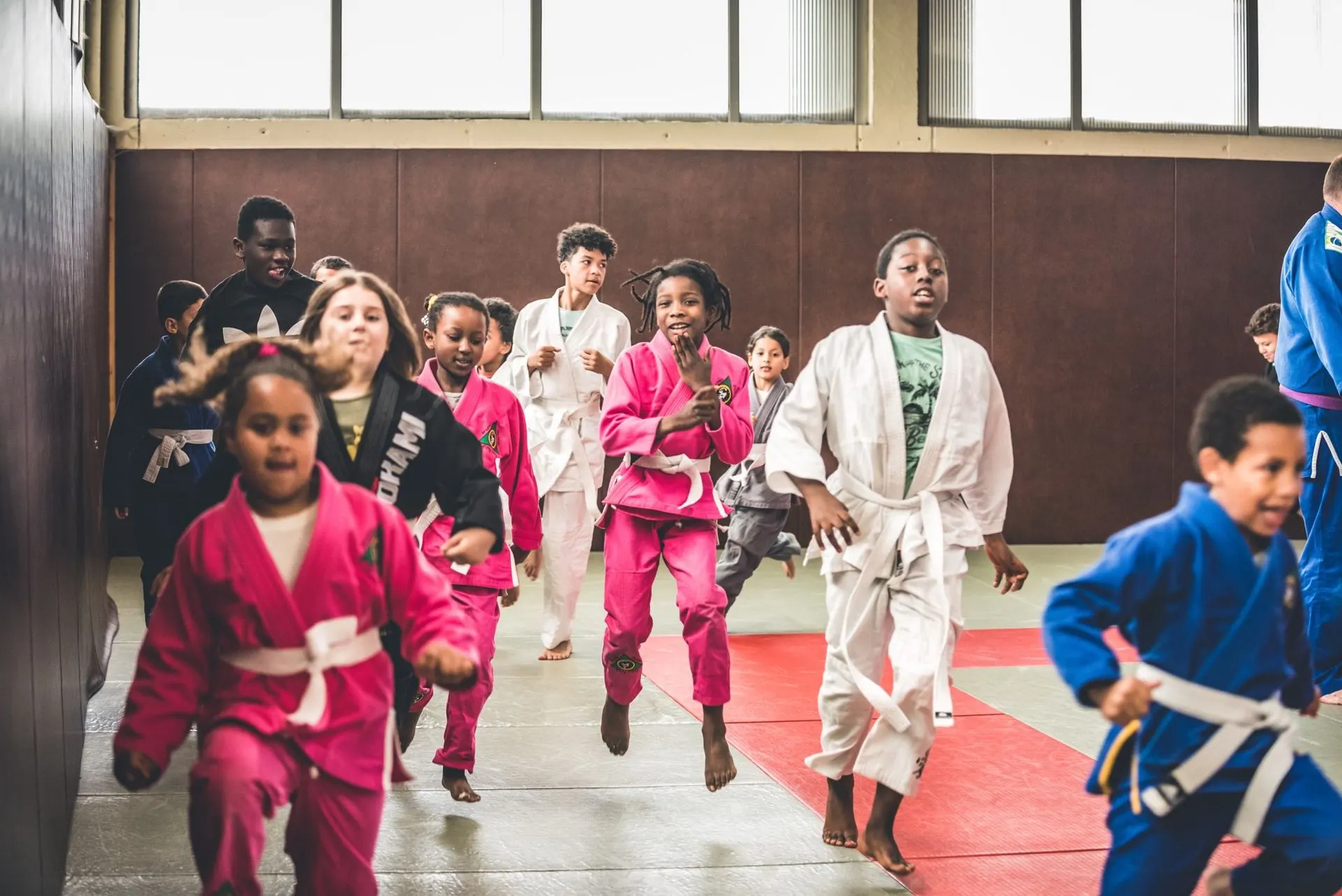Des enfants en kimono rose, bleu et blanc courent sur le tapis