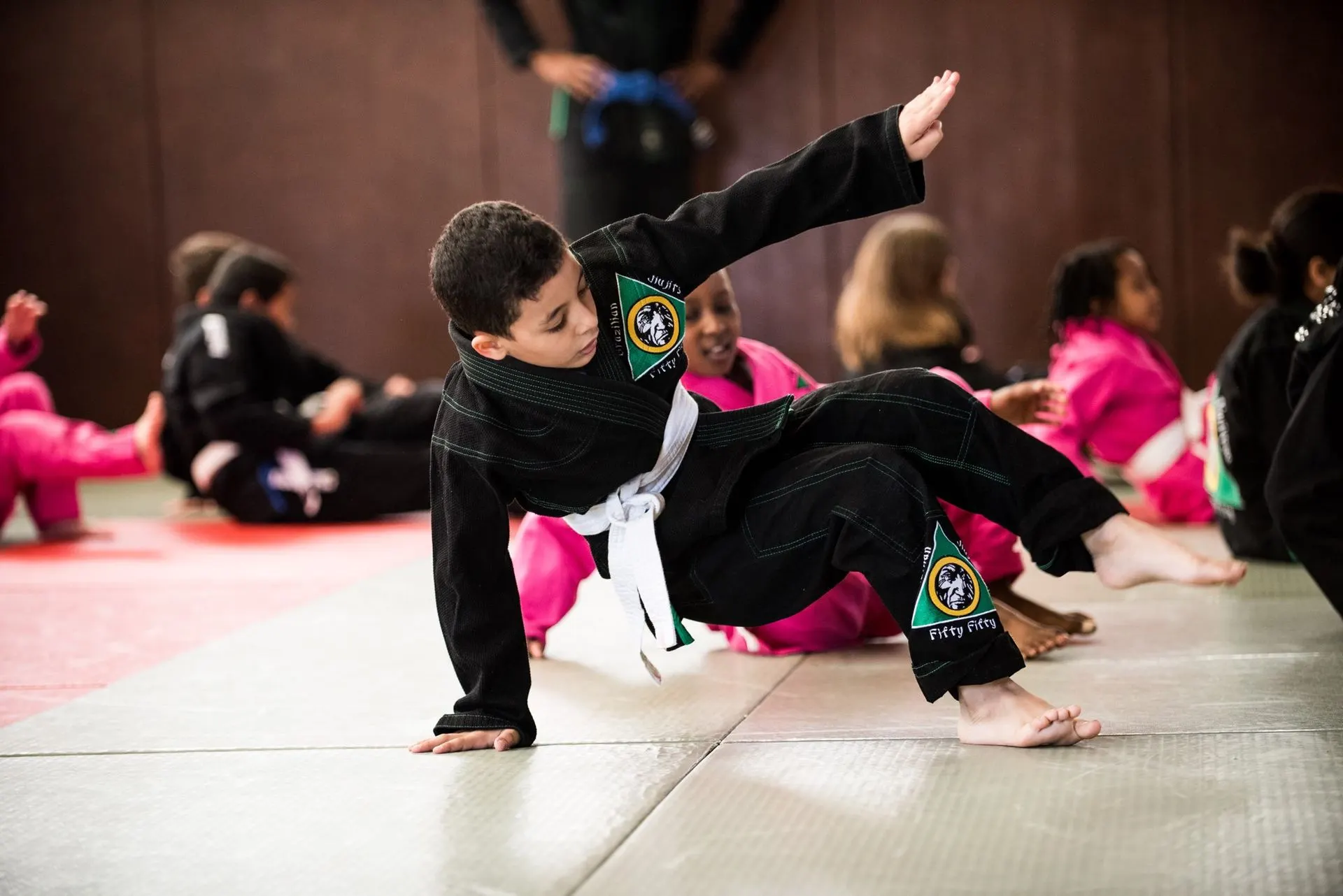 Un enfant en kimono noir roule sur le tapis