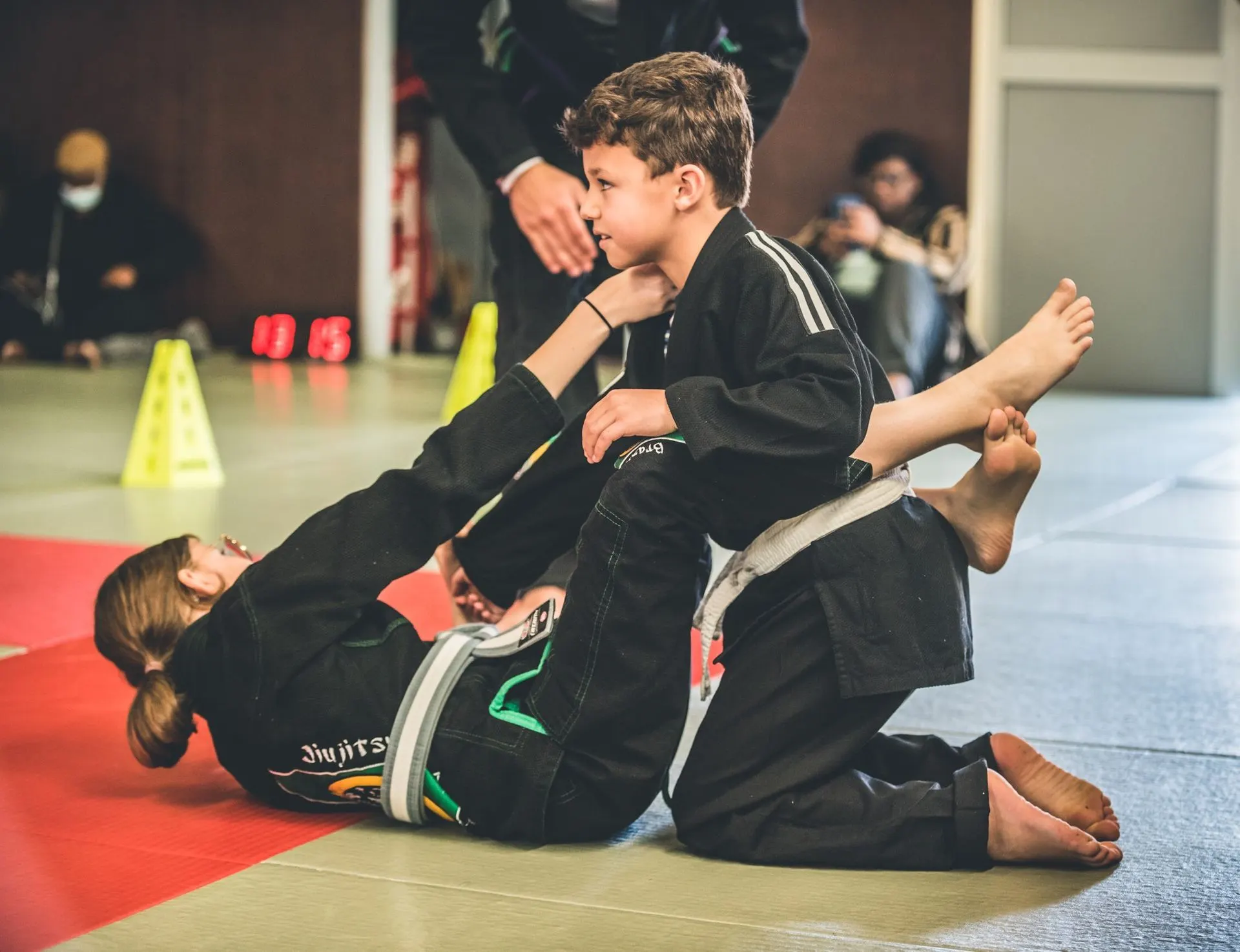 Deux enfants au sol en kimono noir pendant un exercice