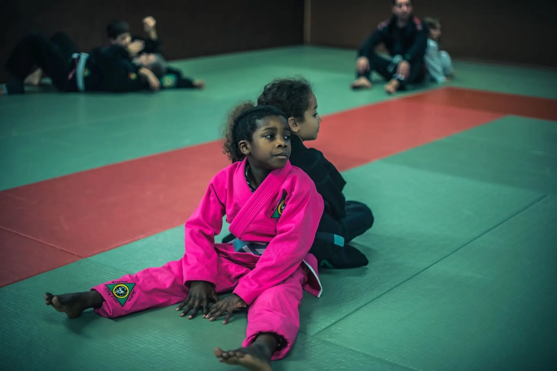 Une petite fille en kimono rose assise sur le tapis vert