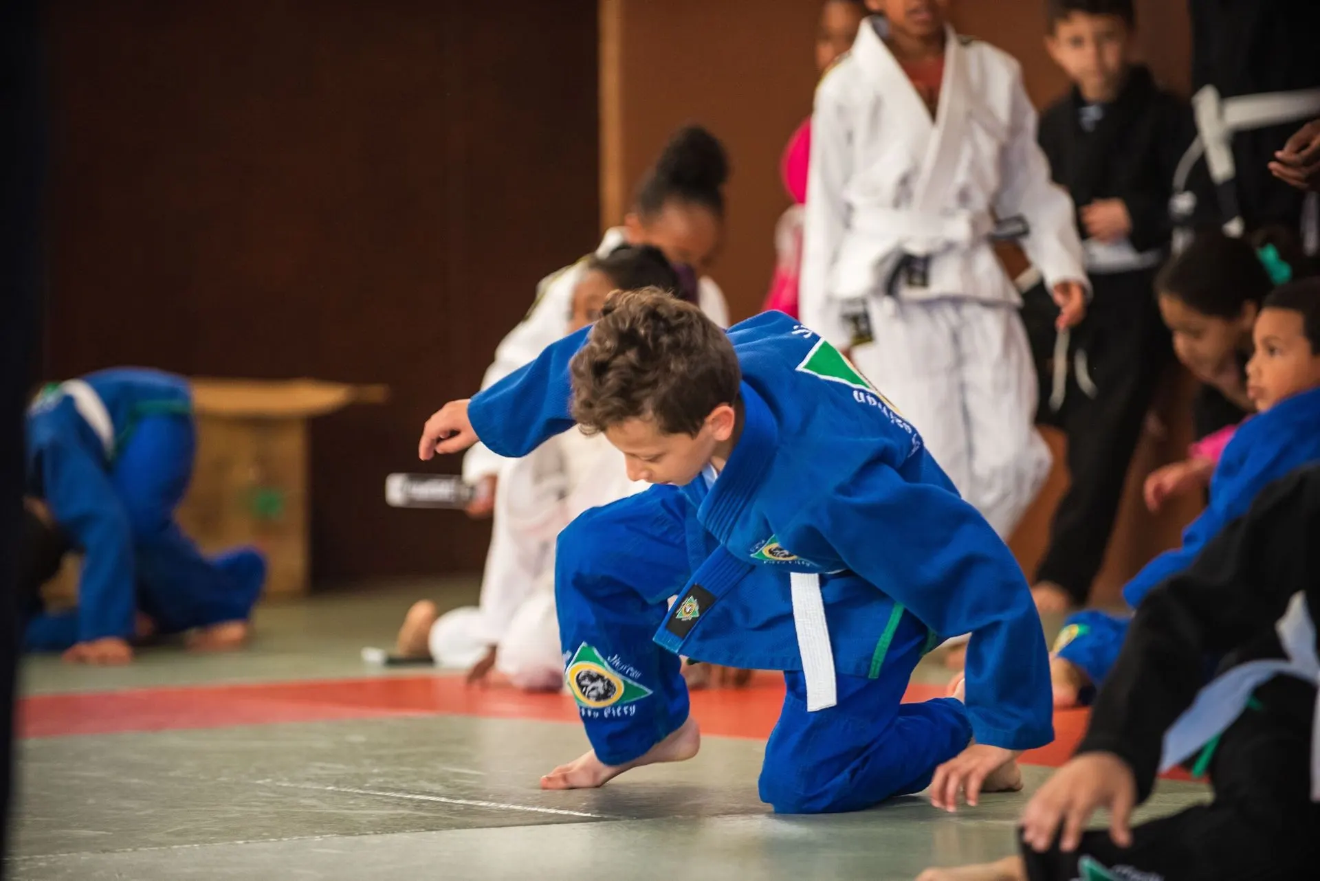 Un enfant en kimono bleu à quatre pattes pendant un jeu d’échauffement