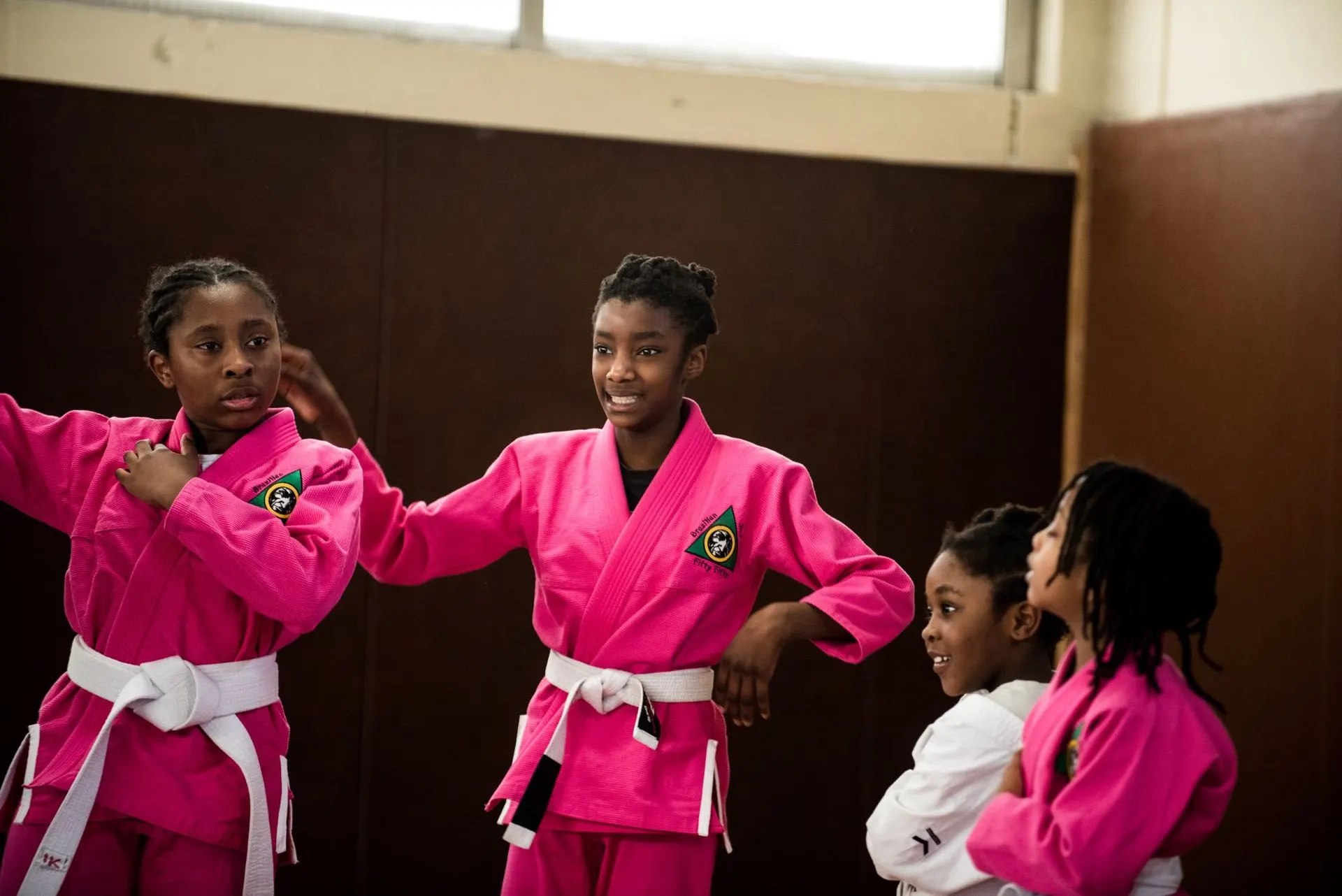 Trois jeunes pratiquantes en kimono rose rient ensemble